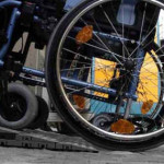 Una carrozzina per disabili spinta su di una pedana per il superamento di una barriera architettonica in una foto d'archivio. ANSA/