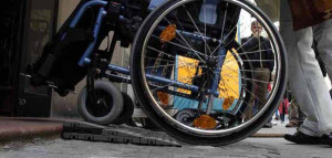 Una carrozzina per disabili spinta su di una pedana per il superamento di una barriera architettonica in una foto d'archivio. ANSA/
