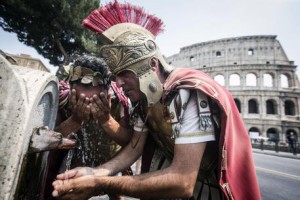 Due centurioni si rinfrescano ad una fontanella davanti il Colosseo per l'ondata di caldo nord africano sulla Capitale, Roma, 3 luglio 2015. ANSA/ANGELO CARCONI