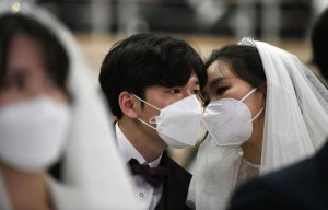 A couple wearing protective face masks attend a mass wedding ceremony organised by the Unification Church at Cheongshim Peace World Center in Gapyeong on February 7, 2020. - South Korea has confirmed 24 cases of the SARS-like virus so far and placed nearly 260 people in quarantine for detailed checks amid growing public alarm. (Photo by Jung Yeon-je / AFP) (Photo by JUNG YEON-JE/AFP via Getty Images)