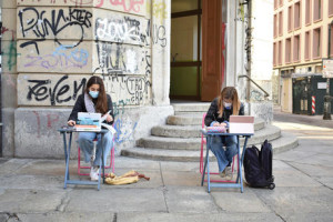 Lisa e Anita, due studentesse della scuola media Italo Calvino di via Sant'Ottavio, sedute al banco in strada, fuori dalla scuola, per protestare contro la didattica a distanza, Torino, 9 novembre 2020. Le due ragazze  hanno deciso di manifestare così il proprio disappunto per la decisione di chiudere le scuole dalla seconda media. Mascherina sul volto, sul banco con libri e quaderni hanno anche un tablet da cui seguono la lezione a distanza. "La scuola è il posto più sicuro, vogliamo tornare in aula - dicono - S'impara di più a guardare i professori negli occhi che in uno schermo al computer". ANSA/ MARCO BOSCATO